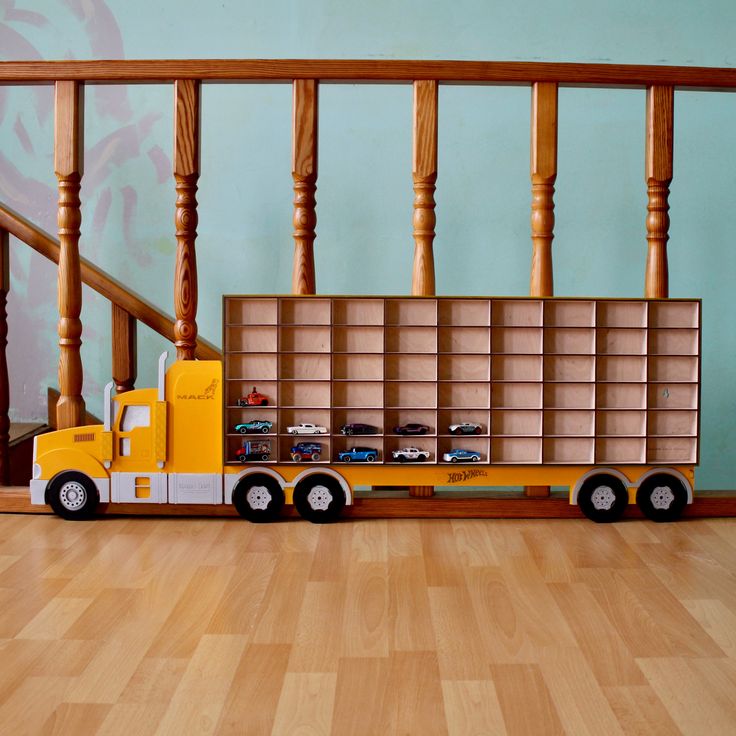 a toy truck is parked in front of a bookshelf on the wooden floor