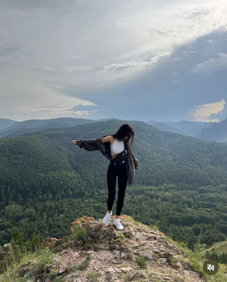 a woman standing on top of a mountain with her arms outstretched