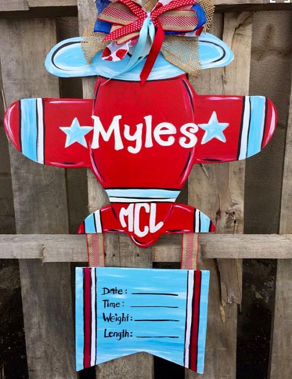 a red, white and blue airplane with the word myles on it hanging from a wooden fence