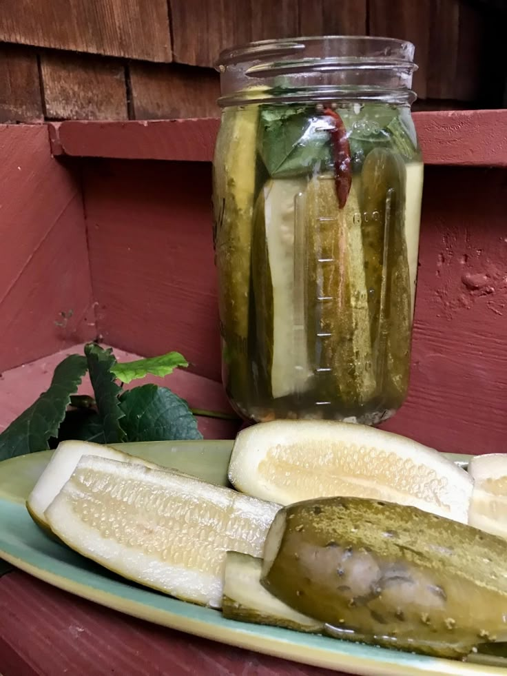 pickles and lemon slices on a plate next to a mason jar