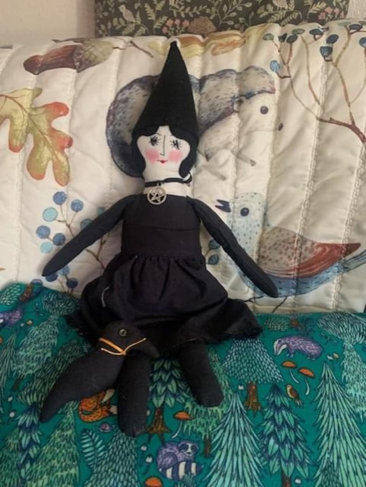 a black doll sitting on top of a bed