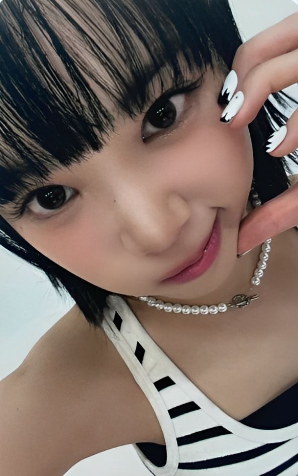 a woman with black and white nail polish holding her hand up to her face while posing for the camera