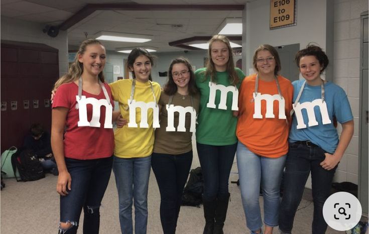 four girls are holding up letters that spell mmm in the shape of letters on their shirts