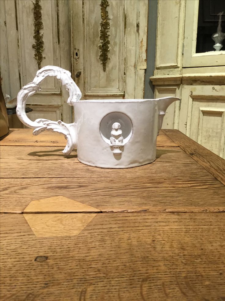 a white pitcher sitting on top of a wooden table