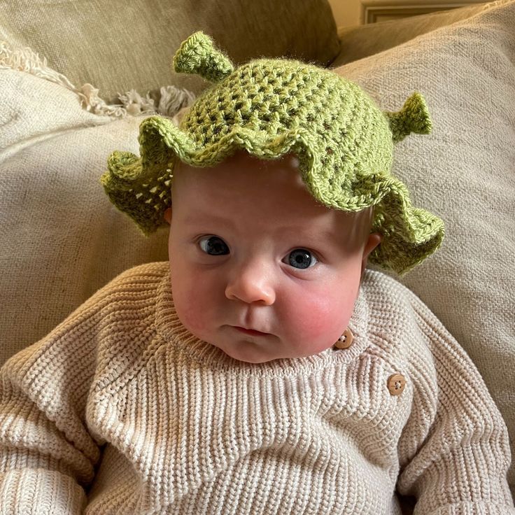 a baby wearing a crocheted hat sitting on a couch