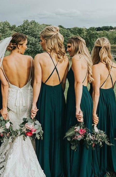 a group of women standing next to each other wearing green dresses and holding bouquets