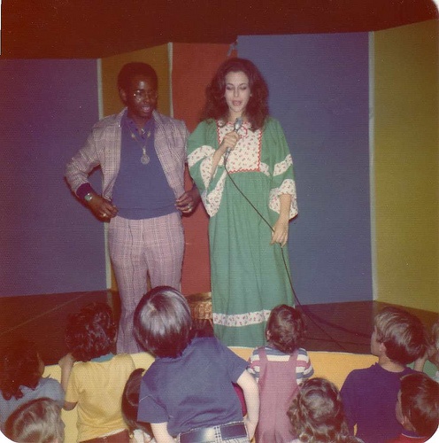 an old black and white photo of two people standing in front of children