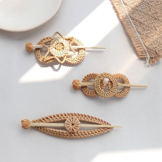 three wooden brooches sitting on top of a white table next to a plate