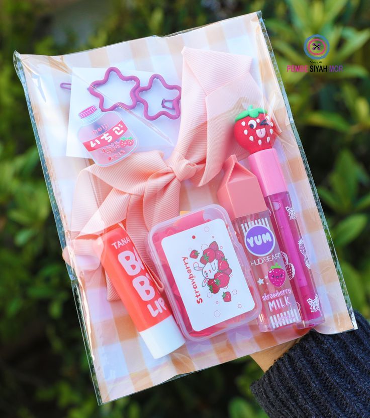 a person is holding a box with various items in it that include lip balm, lipstick, and cookie cutters