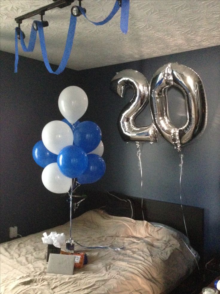 balloons in the shape of numbers hang above a bed with blue and white streamers