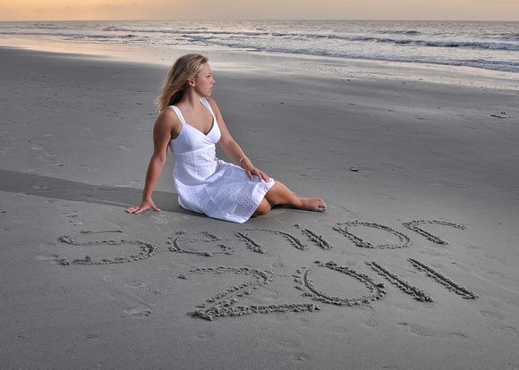 a woman is sitting on the beach writing in the sand