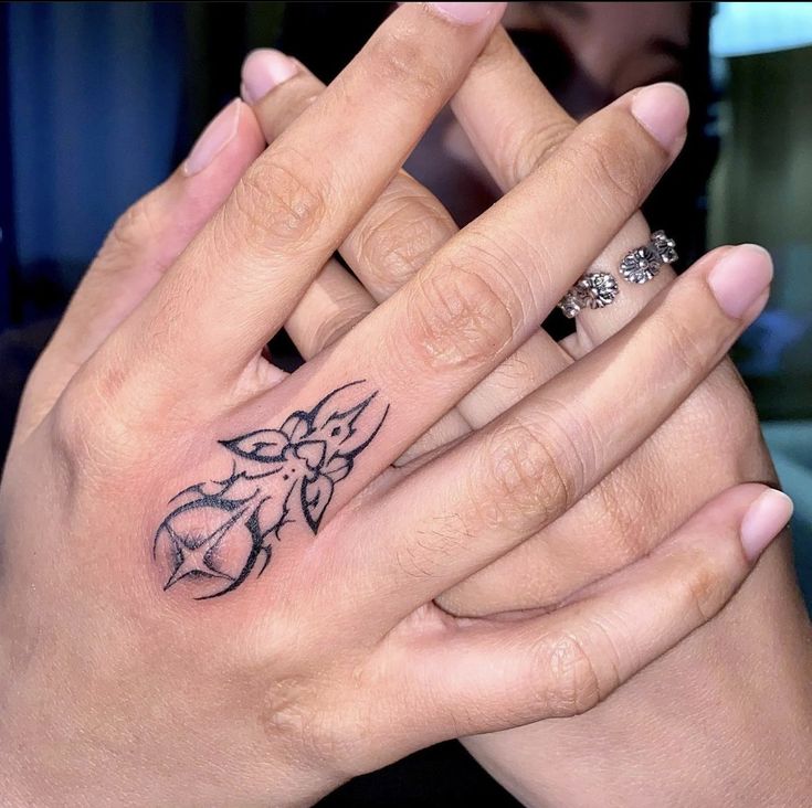 two hands with tattoos holding each other