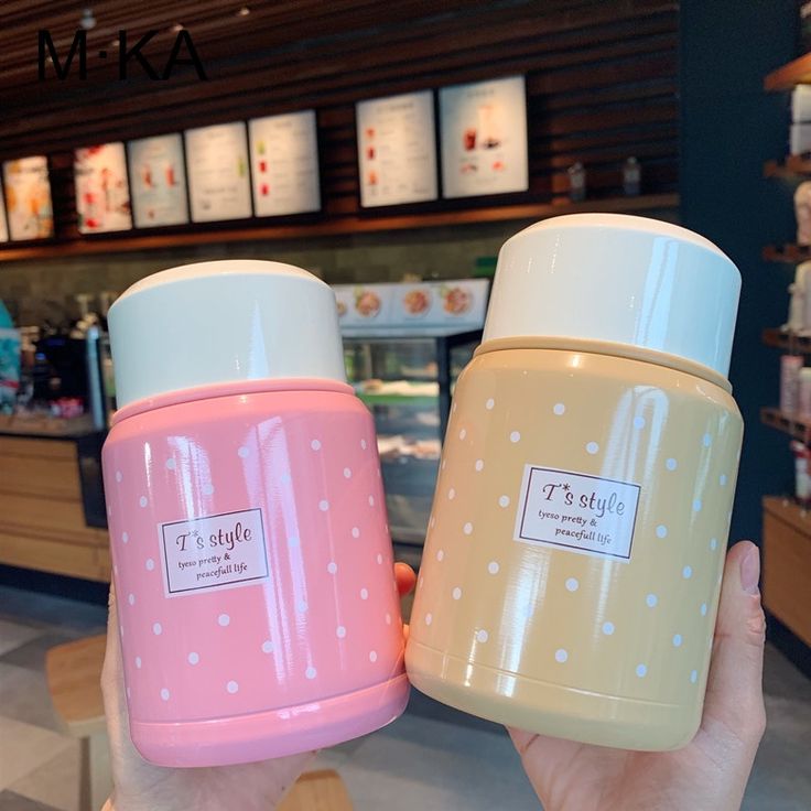 two pink and yellow coffee mugs sitting next to each other in front of a counter