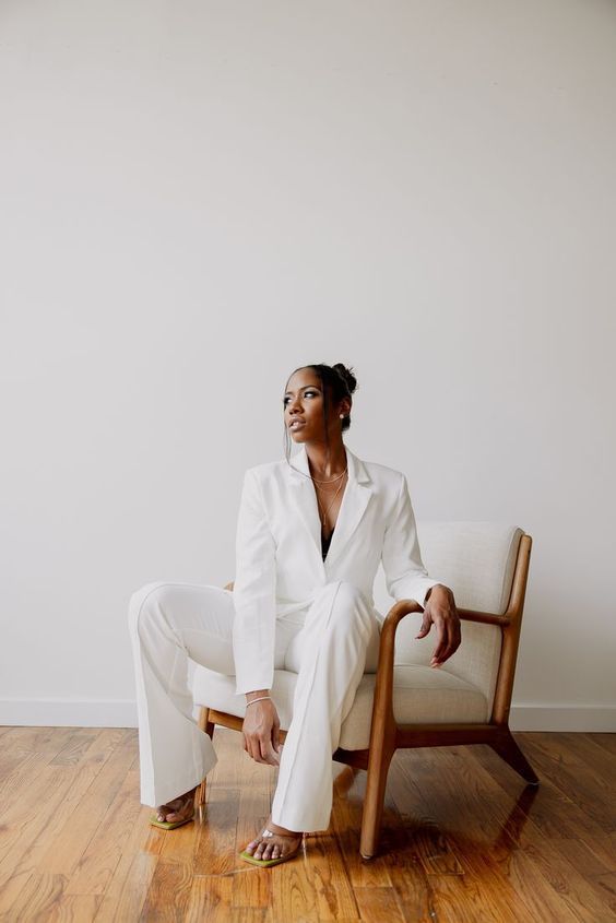 a woman sitting on top of a white chair in a room with wood flooring