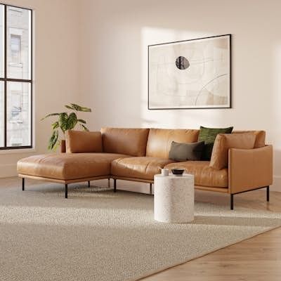 a living room with a brown leather couch and white rug in front of large windows