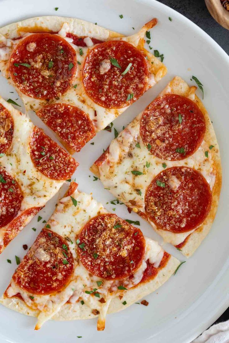 slices of pepperoni pizza on a white plate with parmesan cheese and herbs