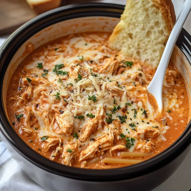 a bowl of chicken parmesan soup with bread on the side