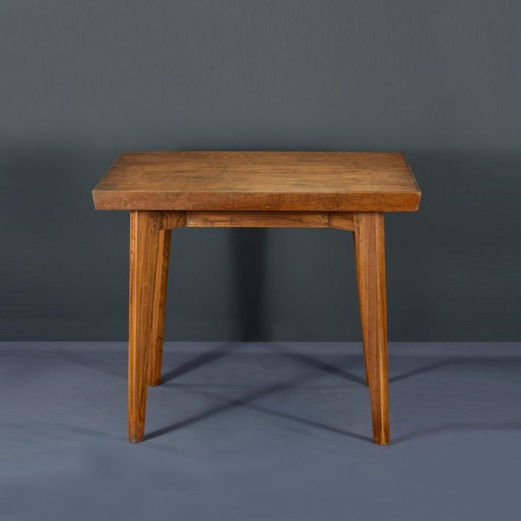 a small wooden table sitting on top of a gray floor