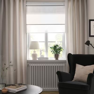 a living room filled with furniture and a window covered in white drapes, next to a coffee table