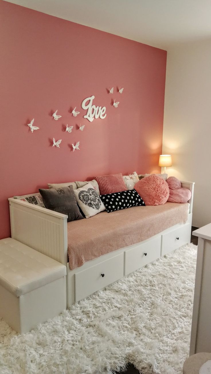 a white day bed sitting in front of a pink wall