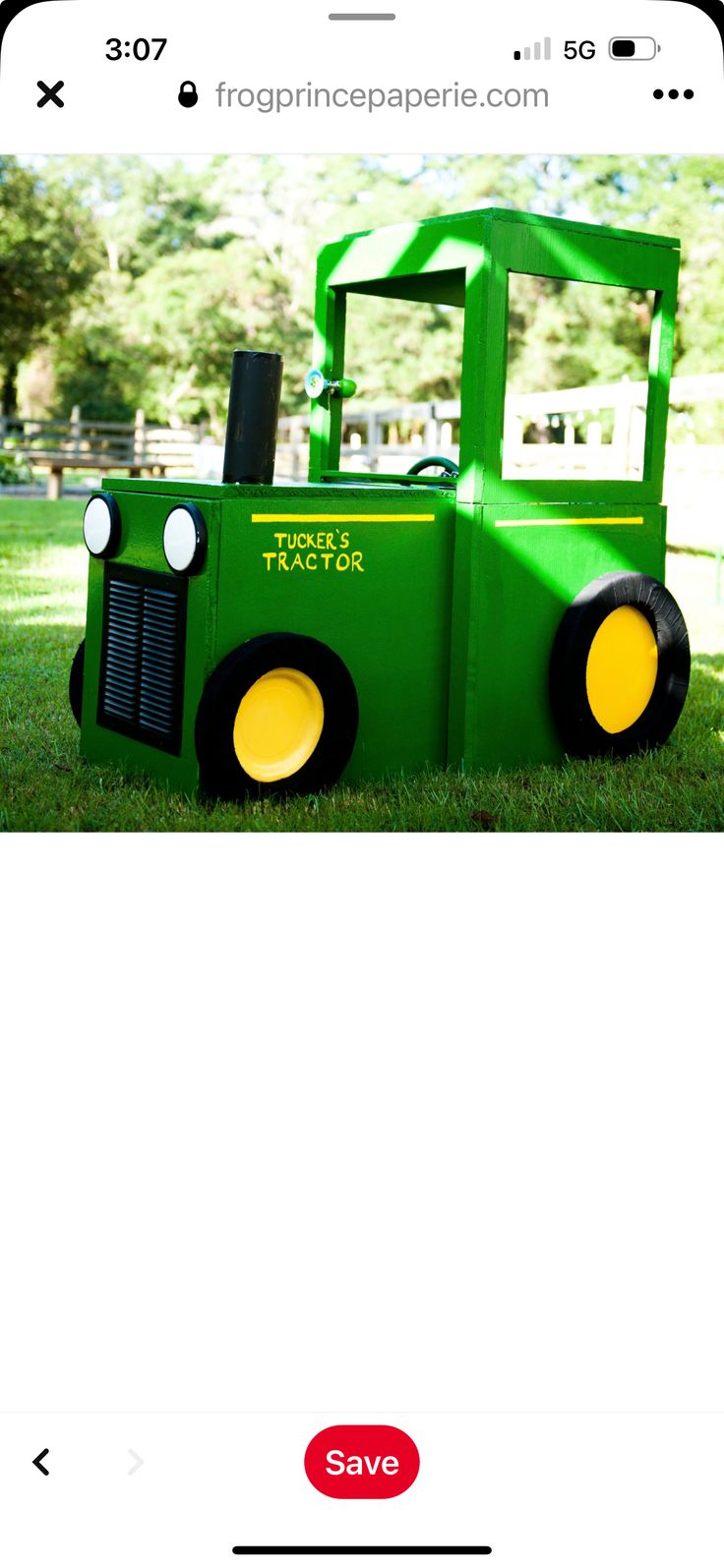 a green tractor made out of cardboard sitting in the grass