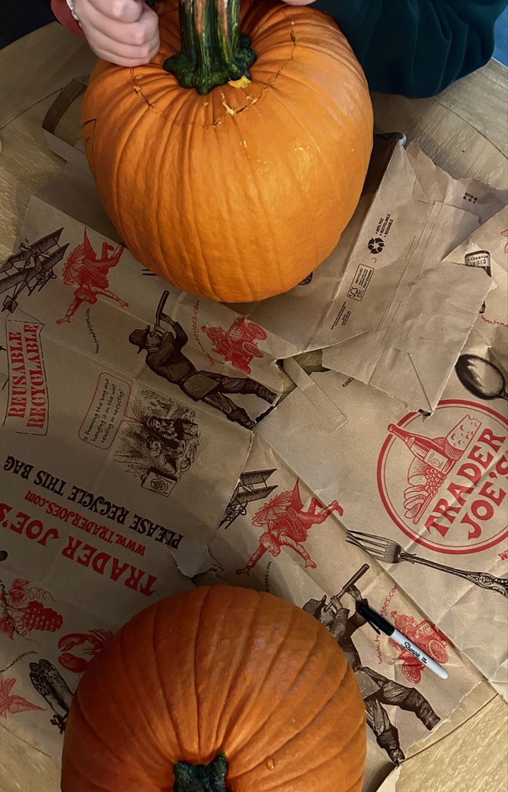 two pumpkins sitting on top of brown paper bags