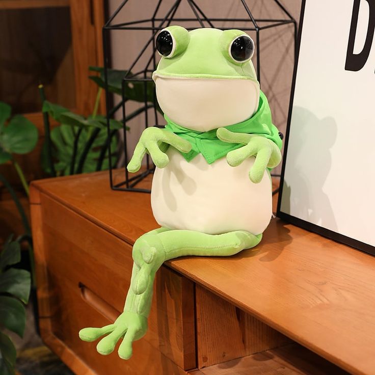 a stuffed frog sitting on top of a wooden table