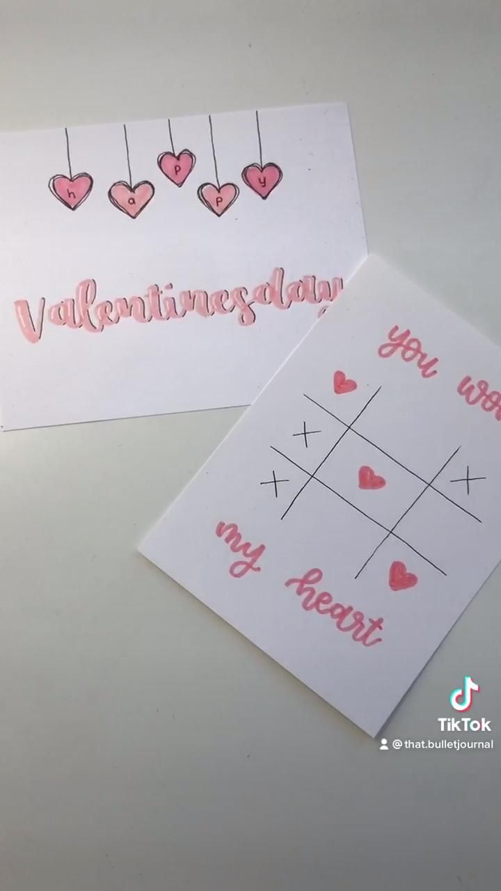 two valentine cards with hearts hanging from strings