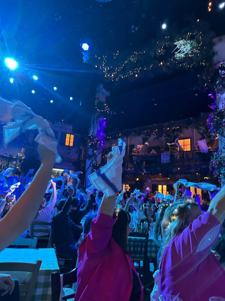 a group of people standing in front of a crowd at a concert with their hands up