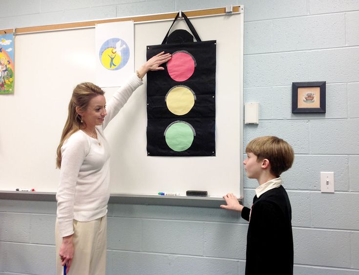 a woman teaching a boy how to use a whiteboard with circles on the wall