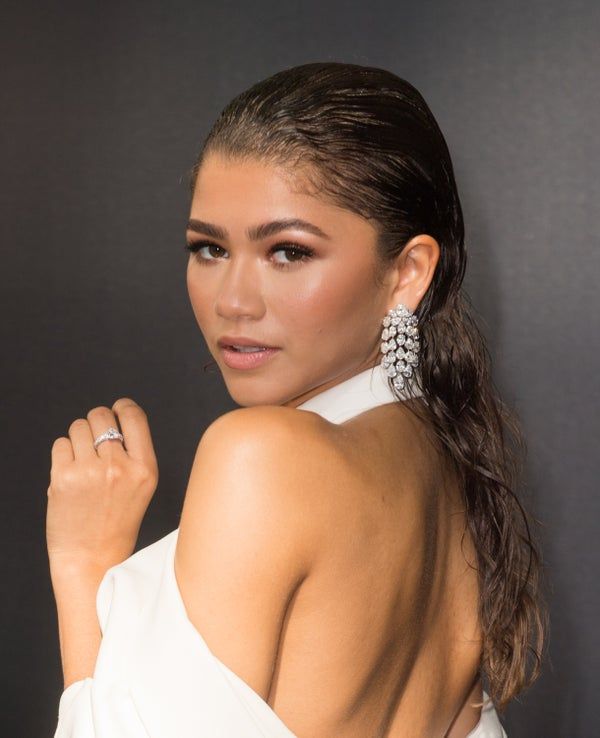 a woman in a white dress posing with her hand on her shoulder and looking at the camera