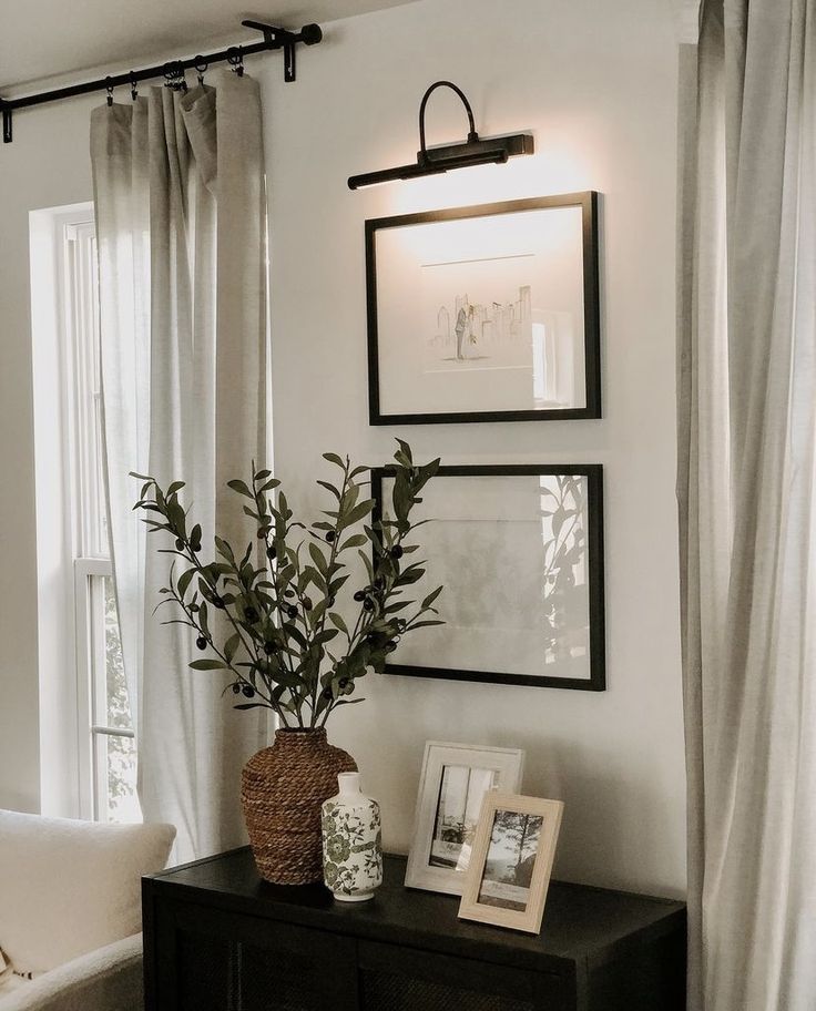 a black and white living room with pictures on the wall, plants in vases