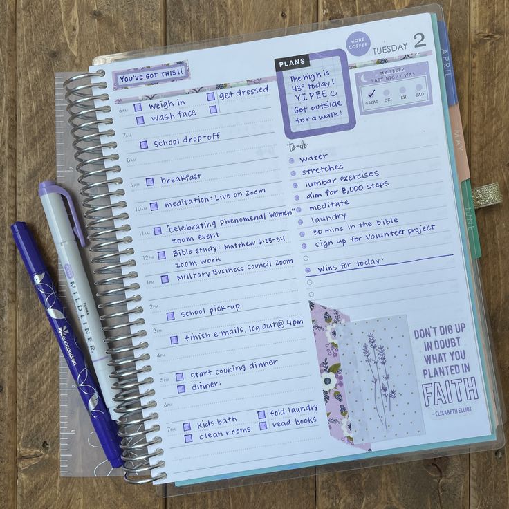 an open planner and pen sitting on top of a wooden table