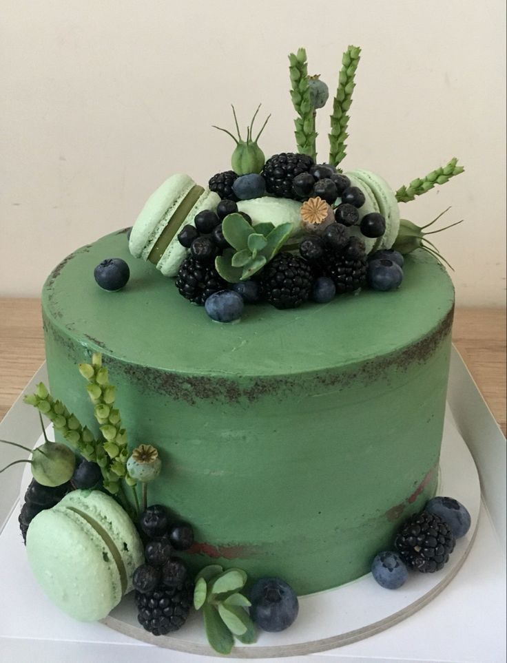 a green cake decorated with berries and succulents