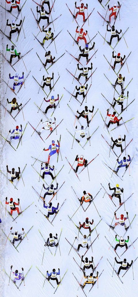 many skiers are in the same position on their skis and one is jumping