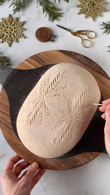 someone is decorating a bread on a wooden platter