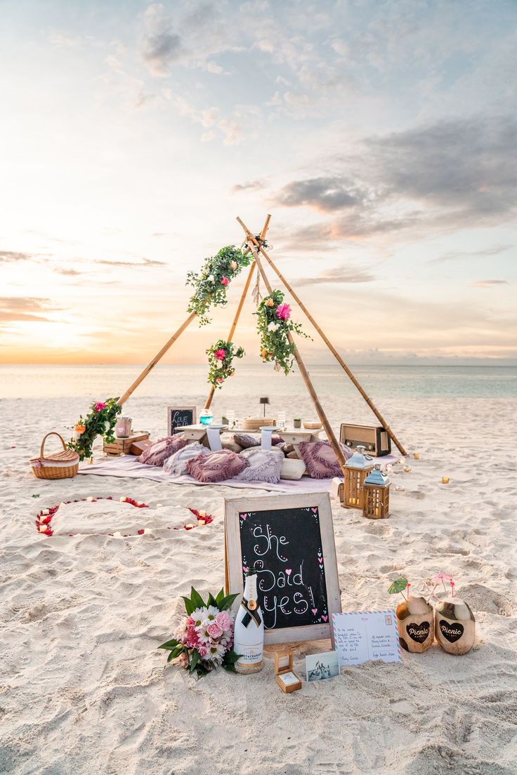 a sign that is on the sand in front of a teepeel with flowers