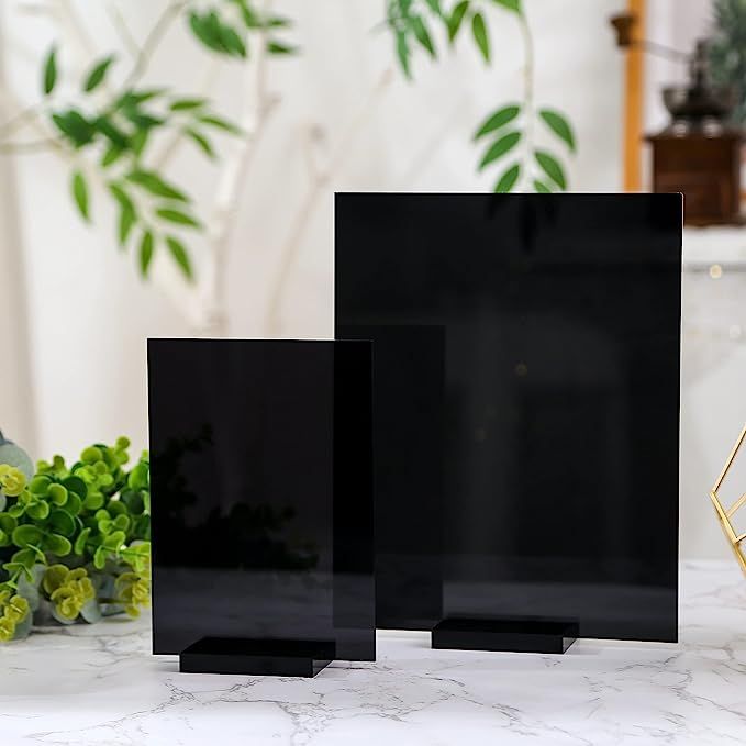 three black square frames sitting on top of a white marble counter next to green plants