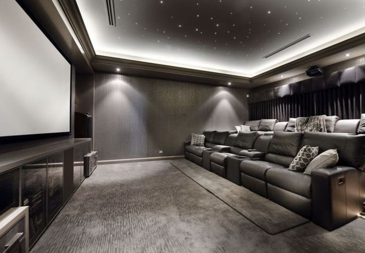 a home theater with leather couches and recliners in front of a projector screen