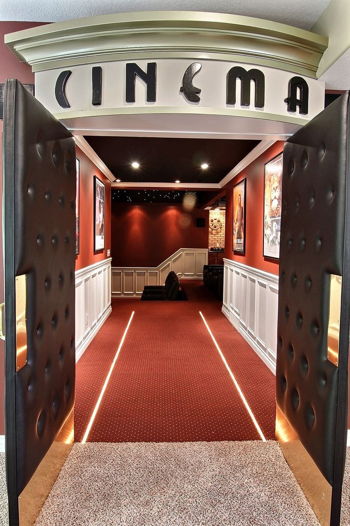 an open door leading to a movie room with red carpet and white trimmings