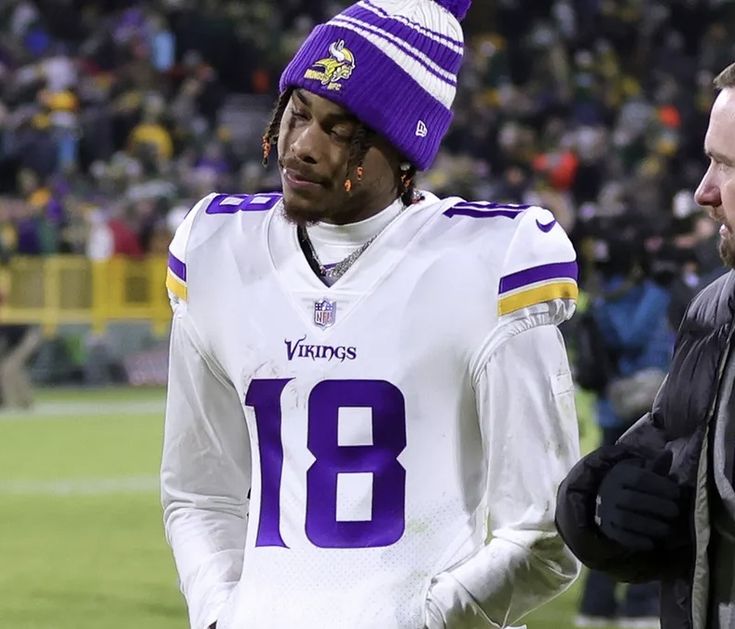 two men standing next to each other in front of a crowd at a football game