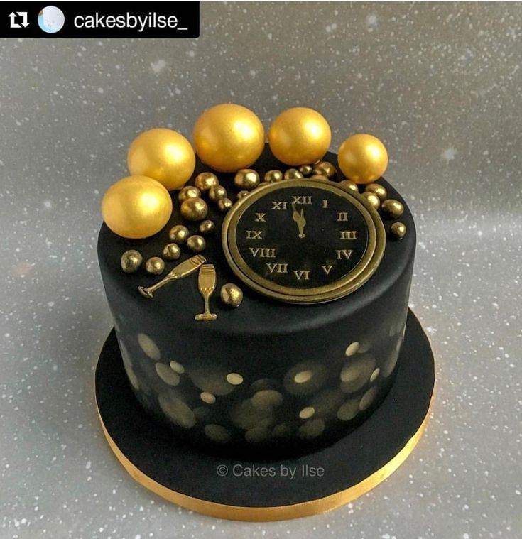 a black cake with gold decorations and a clock on top