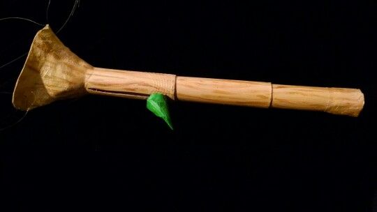 a close up of a wooden object with a green leaf on it's tip