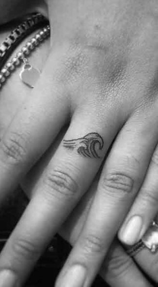 two people with tattoos on their hands holding each other's fingers and one has a small wave tattoo on the middle finger