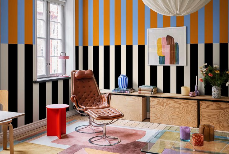 a living room with colorful striped walls and furniture in the corner, including a leather chair