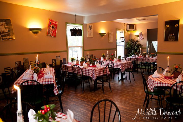 a dining room with tables and chairs covered in checkered tablecloths, lit by candles