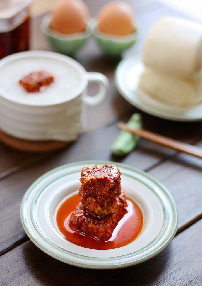 two pieces of food on a plate with sauce and chopsticks next to them