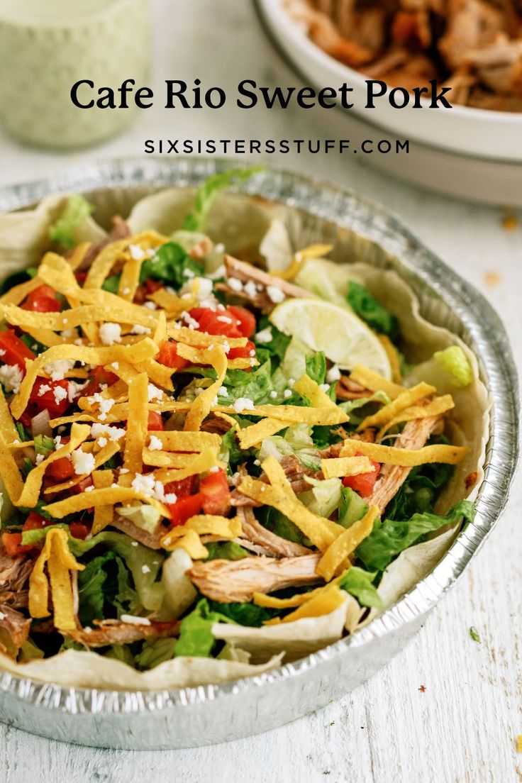 a salad with chicken, lettuce and cheese in a tin foil container on a white table