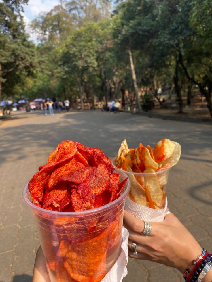 a person holding up a plastic cup filled with food on the side of a road