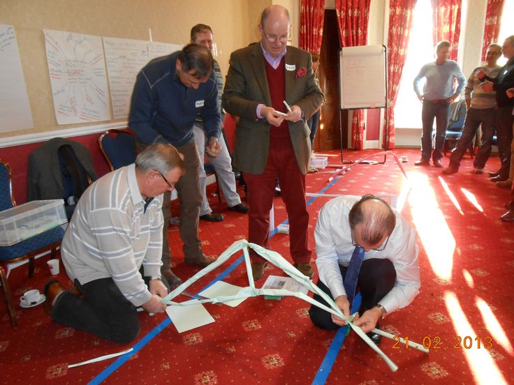 several men are working on an object in the middle of a room with red carpet